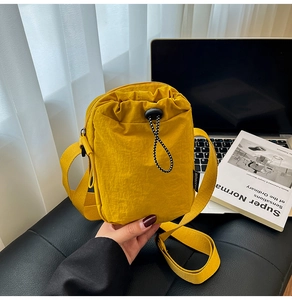 Close-up of yellow nylon crossbody phone bag with black and white drawstring closure