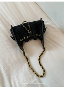 Vue de dessus d'un sac seau en velours noir matelassé avec chaîne dorée et cordon