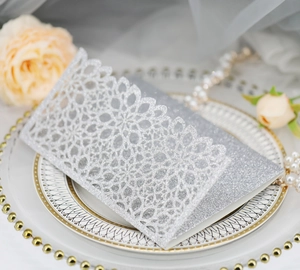 Detail of silver laser cut glitter invitation card with intricate lace floral texture