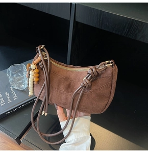Detailed texture of brown suede hobo bag with wooden beads and knotted strap