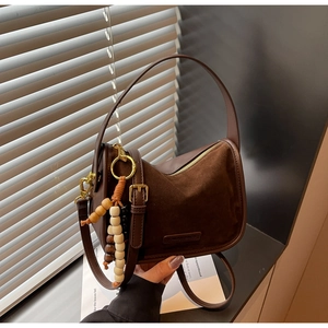 Détail du sac à bandoulière en cuir marron foncé avec daim et perles colorées
