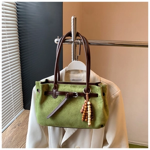 Detail of green frosted tote bag with brown leather handles and ethnic beaded charm