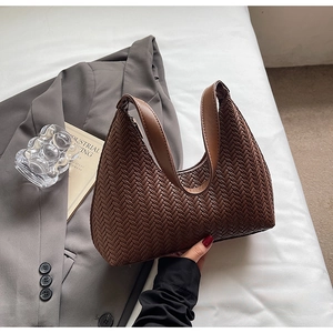 Dettaglio della trama intrecciata della borsa hobo marrone e del manico in pelle liscia