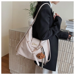 Détail du sac cabas en similicuir blanc cassé avec logo doré et breloque ours en peluche