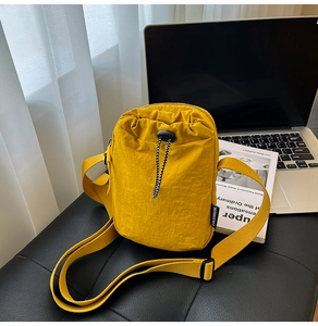 Detail of yellow nylon crossbody phone bag with drawstring closure and fashion tag