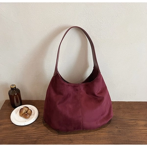 Detail view of burgundy velvet tote bag texture on retro wooden table setting