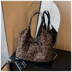 Close-up of leopard print tote bag featuring black bow detail and textured fabric