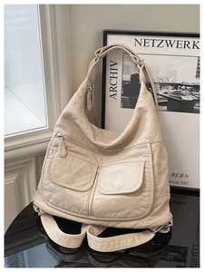 Detail view of the soft faux leather texture and multi-pocket design on the off-white bag