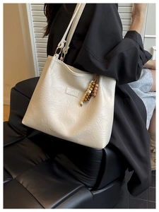 Detail of cream white tote bag with wrinkled texture and vintage wooden bead charm