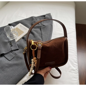 Détail du sac bandoulière marron foncé avec textures cuir mixtes et gland perlé