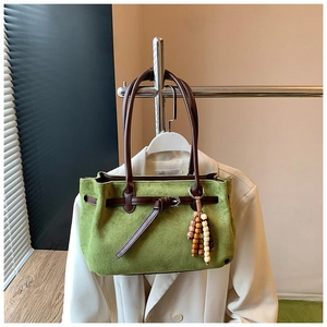 Detail of olive green suede tote bag with brown leather handles and decorative wood beads