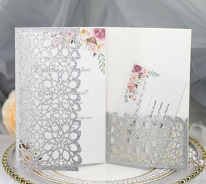 Macro detail of laser-cut floral silver glitter wedding invitation with inner cards