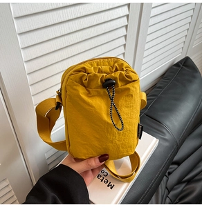 Detail of yellow nylon crossbody phone bag with drawstring and fashion label