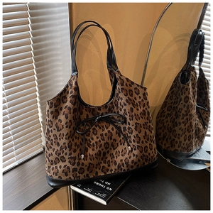 Detail of leopard print tote bag with black ribbon bow and premium leather trim accents
