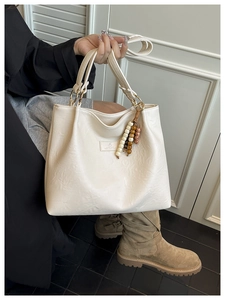 Detail of cream faux leather tote with golden rings and ethnic bead tassel decoration
