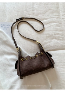 Détail du sac à bandoulière en daim marron avec surpiqûres matelassées et cordon de serrage
