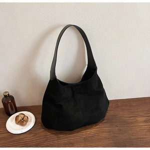 Detail of a vintage black suede hobo tote bag on a wooden table with home decor