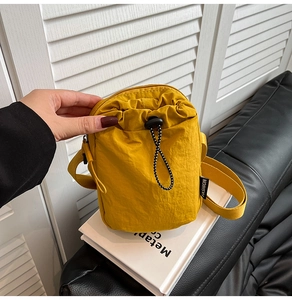 Detail of yellow nylon drawstring crossbody bag with fashion label and adjustable strap