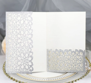 Detail of silver glitter laser-cut wedding invitation card with intricate hollow pattern