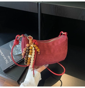 Detail of burgundy suede crescent bag featuring retro quilted texture and beaded tassel