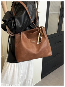 Detail of vintage brown leather tote bag with wood bead tassel and brand patch