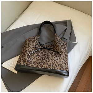 Close-up of leopard print tote bag with black leather trim and delicate bow detail