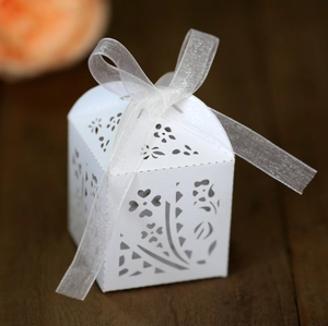 Close-up of laser-cut flower patterns and white ribbon bow on elegant wedding candy box