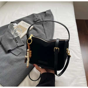 Détail du sac patchwork en cuir et daim noir avec élégant pendentif en perles de bois