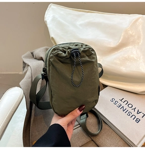 Close-up of army green nylon mini crossbody bag with drawstring toggle and adjustable strap