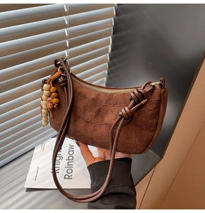 Macro shot of dark brown suede crescent bag featuring retro wooden bead tassel details