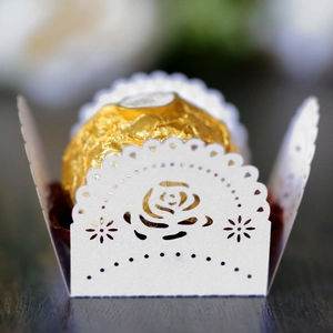 Macro view of white laser-cut paper lace wrap with intricate rose pattern for chocolates