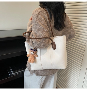 Detail of white tote bag with soft pleated texture and a cute brown bear charm