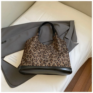 Detail of the leopard print fabric and black leather handles on a large tote bag