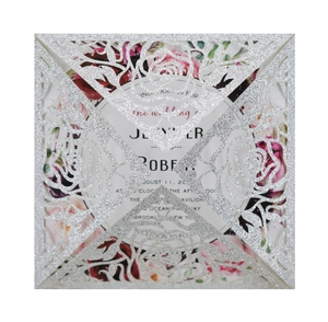 Macro detail of laser-cut rose glitter paper wedding invitation with floral inner card