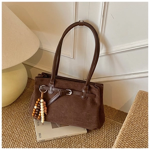 Detail view of dark coffee suede tote bag with wood bead charm and metal buckle
