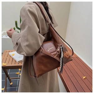 Gros plan du sac cabas en cuir marron avec charme d'ours en peluche et foulard à carreaux