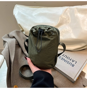 Detail of army green nylon mini crossbody bag with drawstring and zip closure