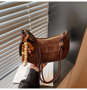 Detail of dark brown suede hobo bag with vintage wooden bead tassel and zipper top