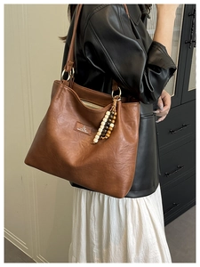 Brown vintage shoulder bag detail with leather texture and decorative beaded keychain