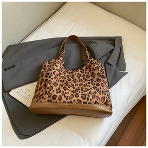 Detail view of the leopard print tote bag with brown leather handles and reinforced base