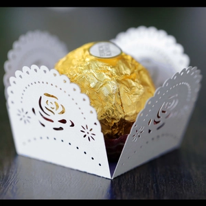 Detail of laser-cut white paper lace wrapper with rose patterns for wedding chocolates