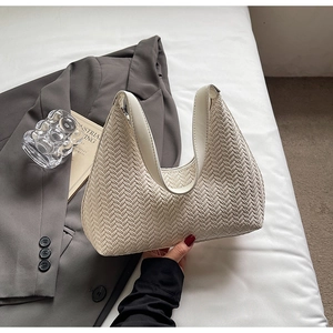 Dettaglio borsa hobo intrecciata a mano color crema con trama chevron e manico largo