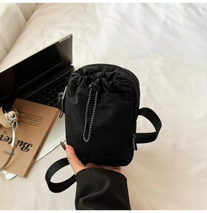 Detail of black nylon phone bag with drawstring closure and fashion woven label