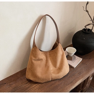 Detailed texture of brown suede hobo bag with vertical stitching on vintage wood surface