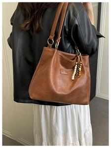 Detail of vintage caramel leather tote bag with wooden bead tassel and gold metal hardware