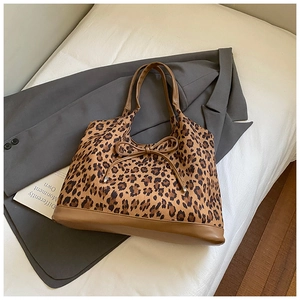 Detail of leopard print tote bag featuring a bow accent and brown leather handles