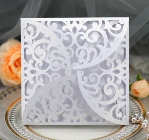 Detail of laser-cut white pearlescent paper invitation with ornate floral patterns