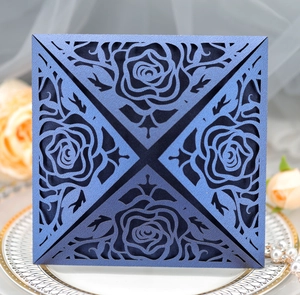 Detailed laser-cut navy blue floral invitation on a decorative plate with pearls