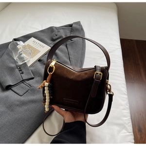 Détail du sac à main marron foncé en daim avec perles en bois et ferrures dorées chic