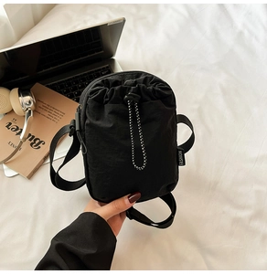 Detail of black nylon crossbody phone bag with drawstring closure and fashion label